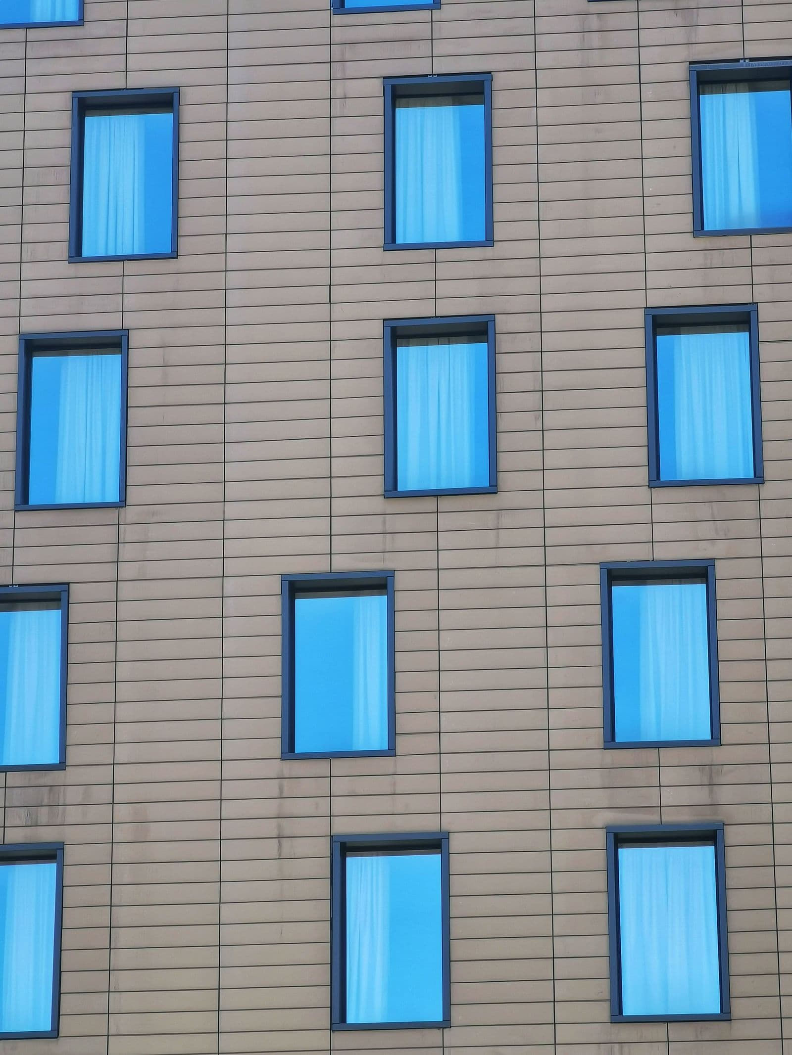 Staggered blue windows set into a pale building facade